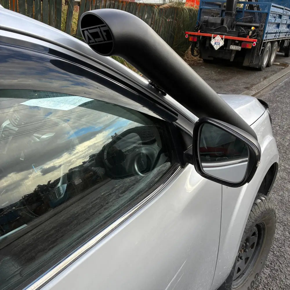 Close-up of a car's side mirror with a tow truck in the background