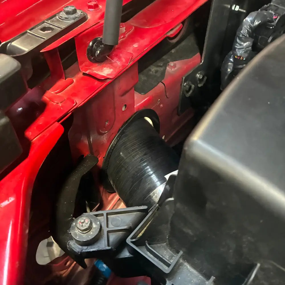 Close-up of a red vehicle's engine bay with various components.