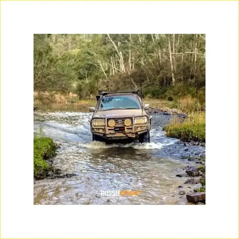 Brown rugged toyota landcruiser fj105 with premium rockarmor bullbar and rock sliders driving through shallow water
