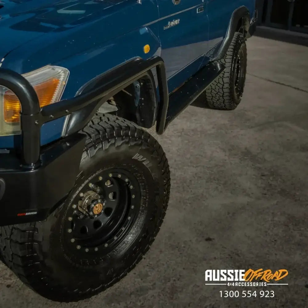 Blue Toyota Landcruiser 78 Series V8 troop carrier with rockarmor steel rockslider side steps and black bull bar wheels
