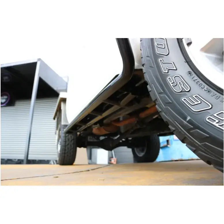 Vehicle undercarriage showing tires with a black rockarmor brushbar for toyota hilux 2005 plus premium steel rockslider