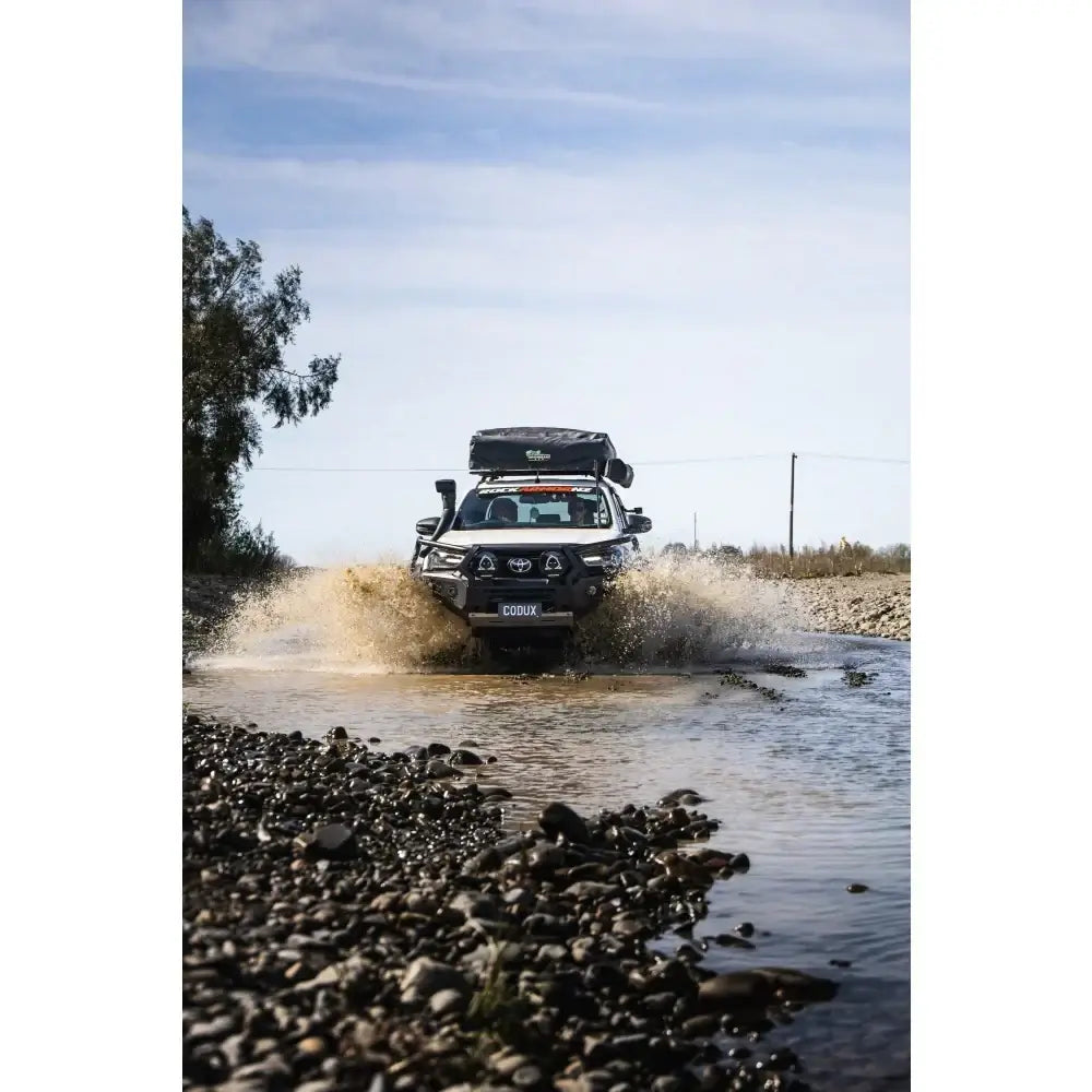 White toyota hilux wading through water equipped with rockarmor gt steel hoop bullbar combo pack and synthetic winch rope