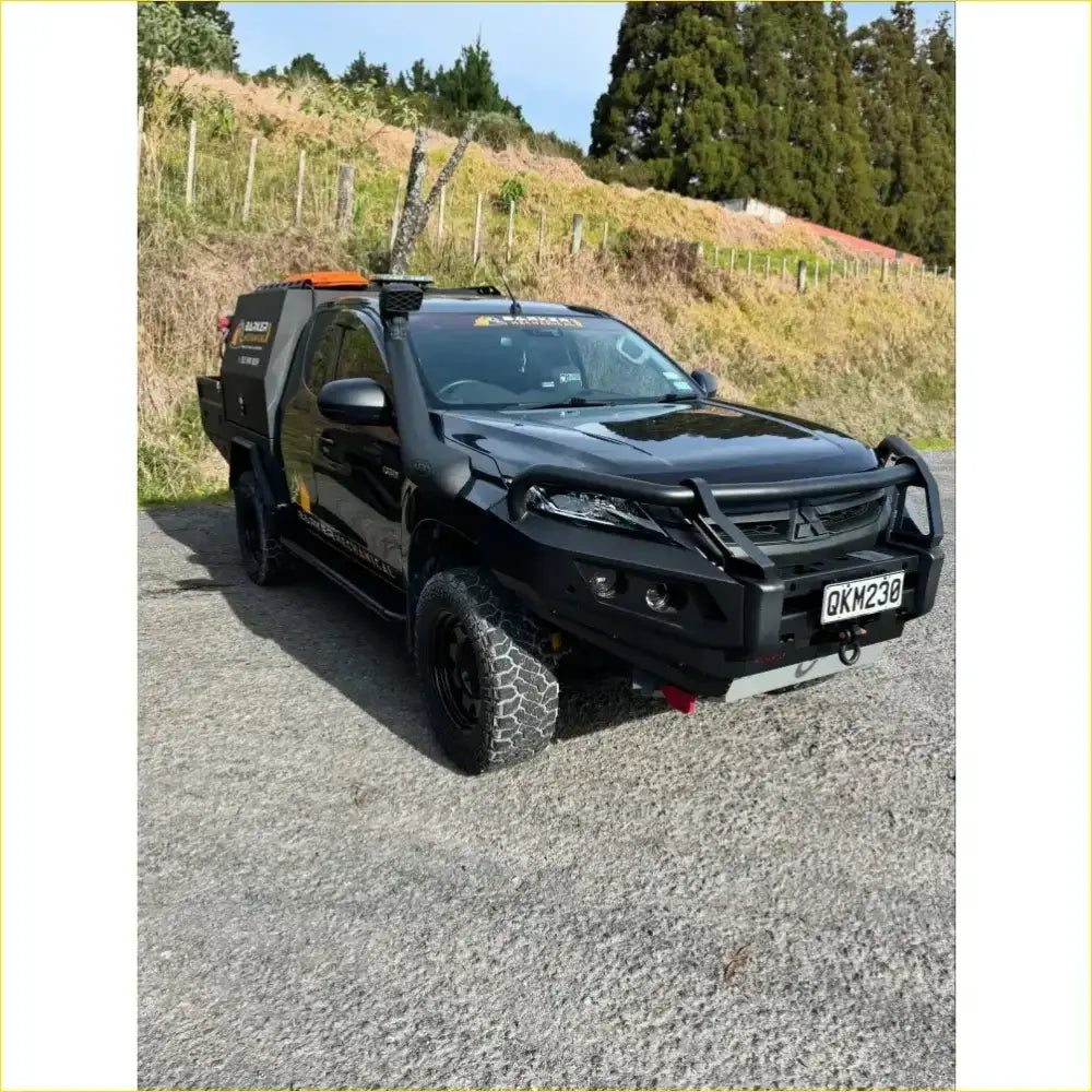 Black mitsubishi triton pickup with gt hoop bullbar and rock sliders featuring rugged off-road tires and reinforced bumper
