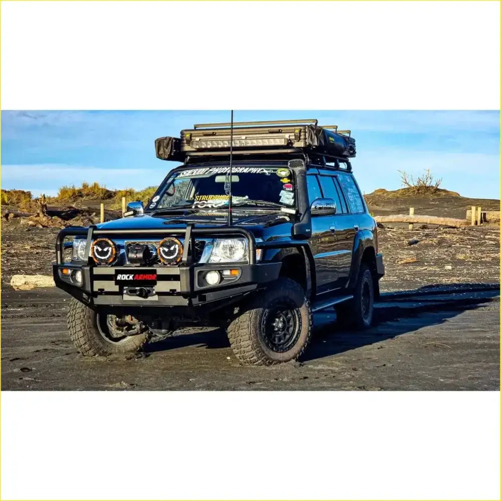 Black nissan patrol gu4 with rockarmor rock pack premium bullbar roof rack and rugged off-road tires side view