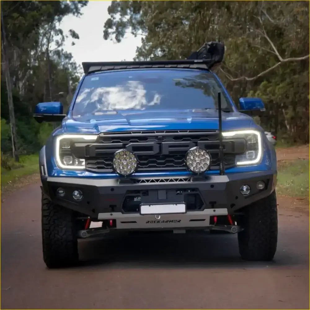 Blue ford ranger wildtrak with black front bumper and roof rack featuring rockarmor gt hoopless bullbar and rock sliders