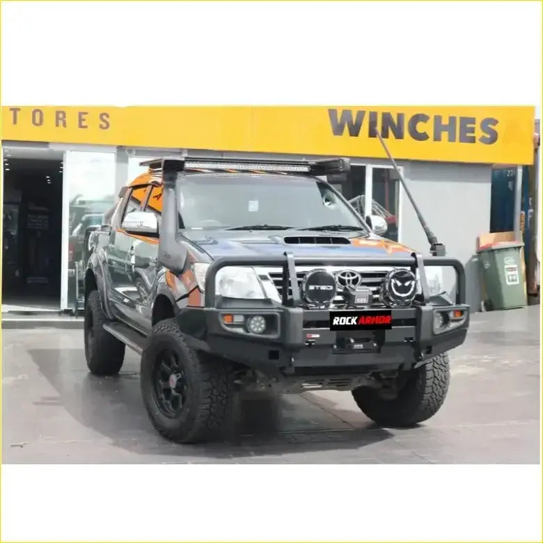 Black toyota hilux 2011-15 with premium rockarmor rock pack bullbar and rock sliders featuring orange accents