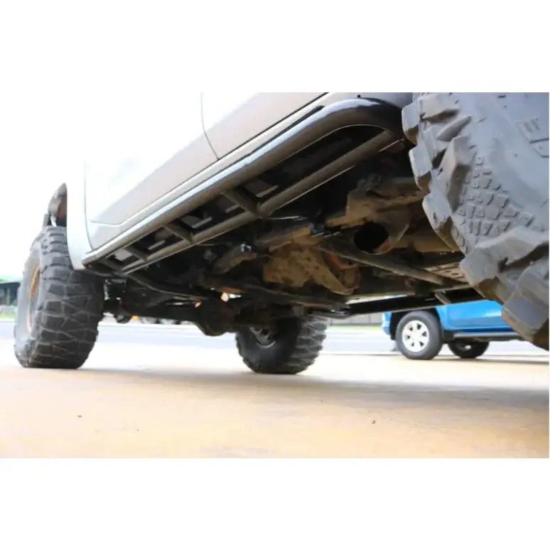 Truck undercarriage with oversized tires showcasing rockarmor steel rockslider side steps for nissan patrol y61 gu1 gu4