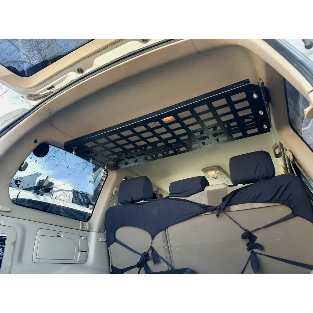 A black metal rear cargo shelf installed in the interior of a Toyota Landcruiser 100 series vehicle.